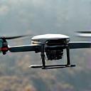 A professional survey drone in flight over a rugged landscape.